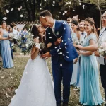 les mariés qui s'embrasse, robe blanche et costume bleu marine clair