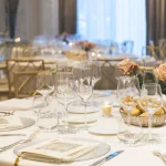 Table de mariage, nappe, vaisselle blanche, au centre bouquet de rose saumon clair